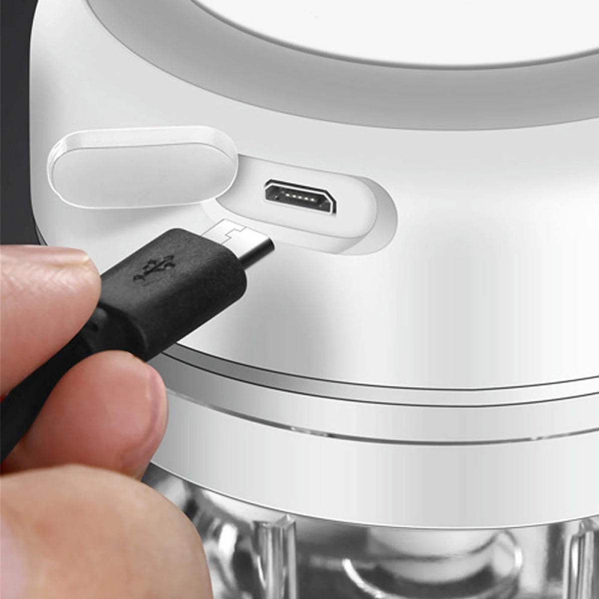 A finger holds a black USB cable being plugged into a white charging port.
