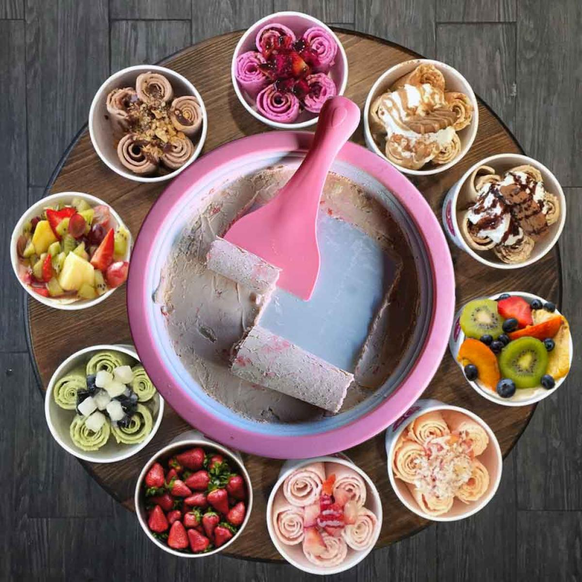 Kleurrijke rol-ijsgerechten en een kom met vers fruit op een houten tafel.