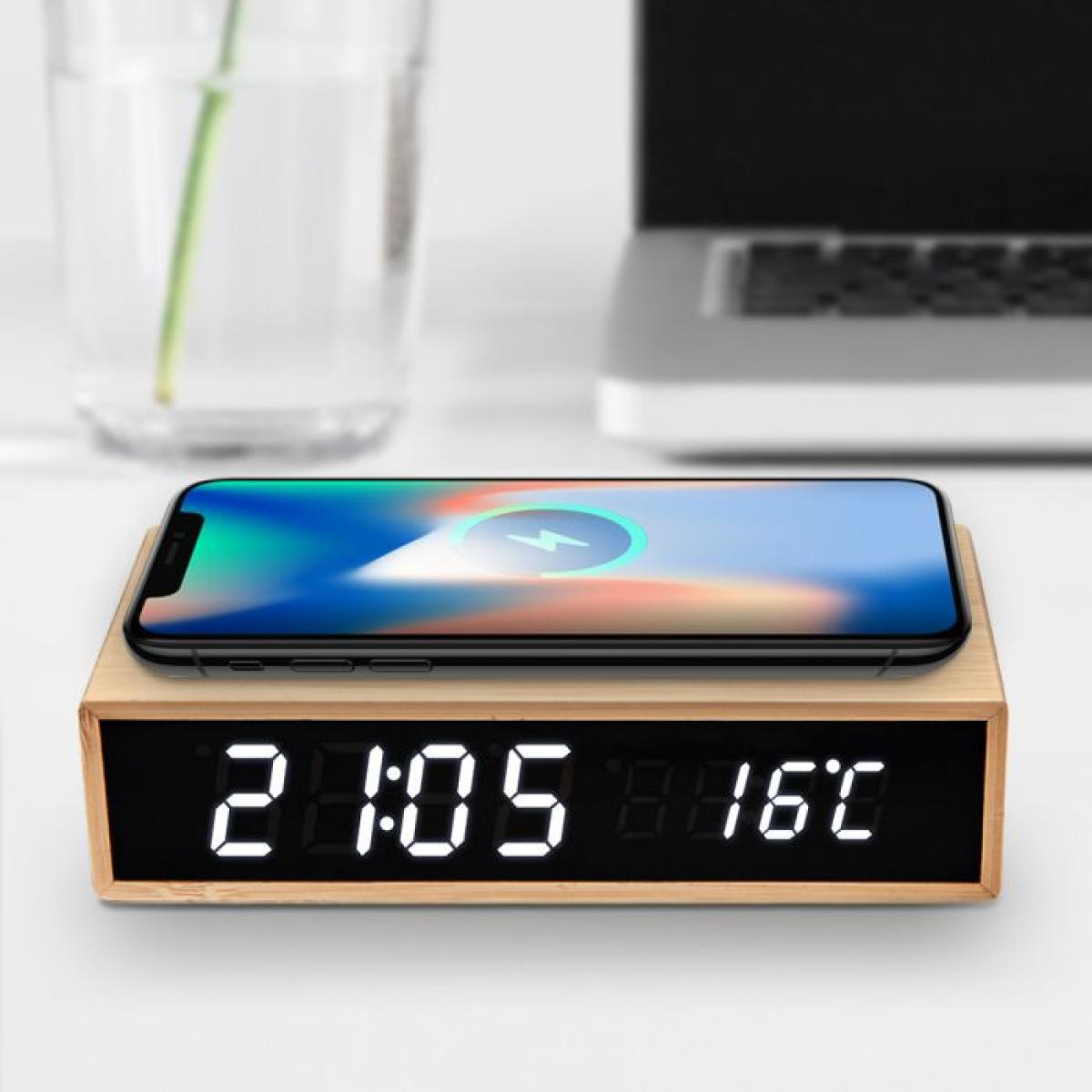 A smartphone charging on a wooden digital alarm clock.
