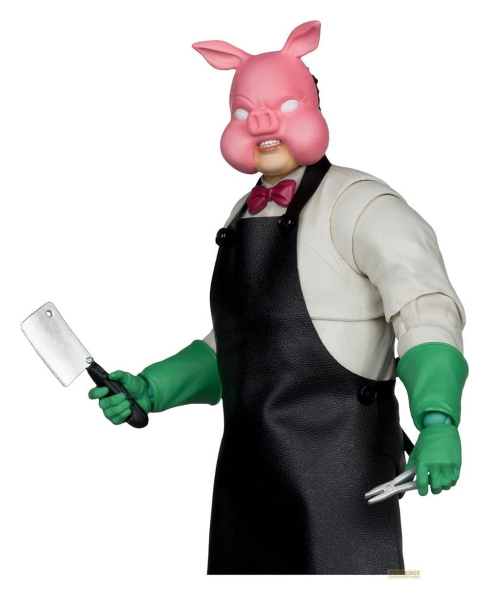 Eine Figur mit Schweinemaske, Schürze, Handschuhen und Werkzeugen.