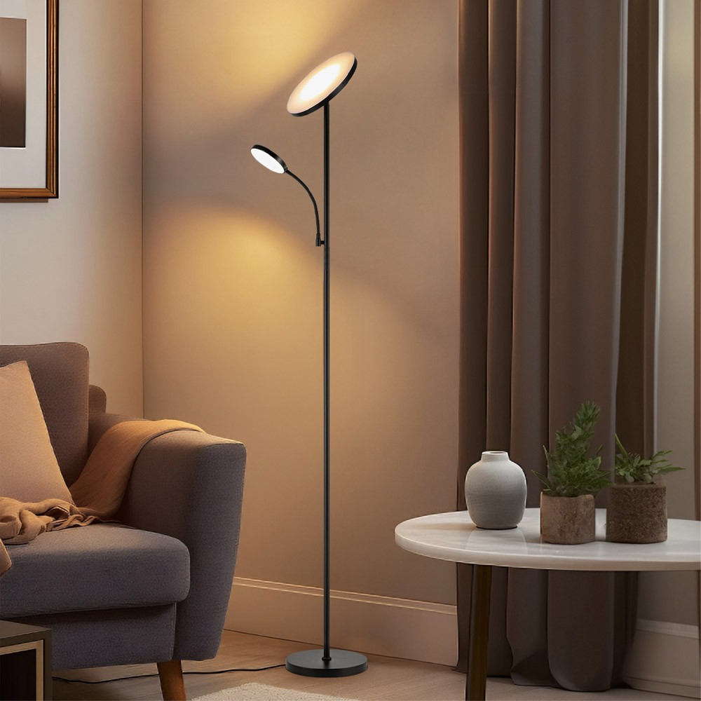 Una lámpara de pie moderna negra con dos luces está junto a un sillón.