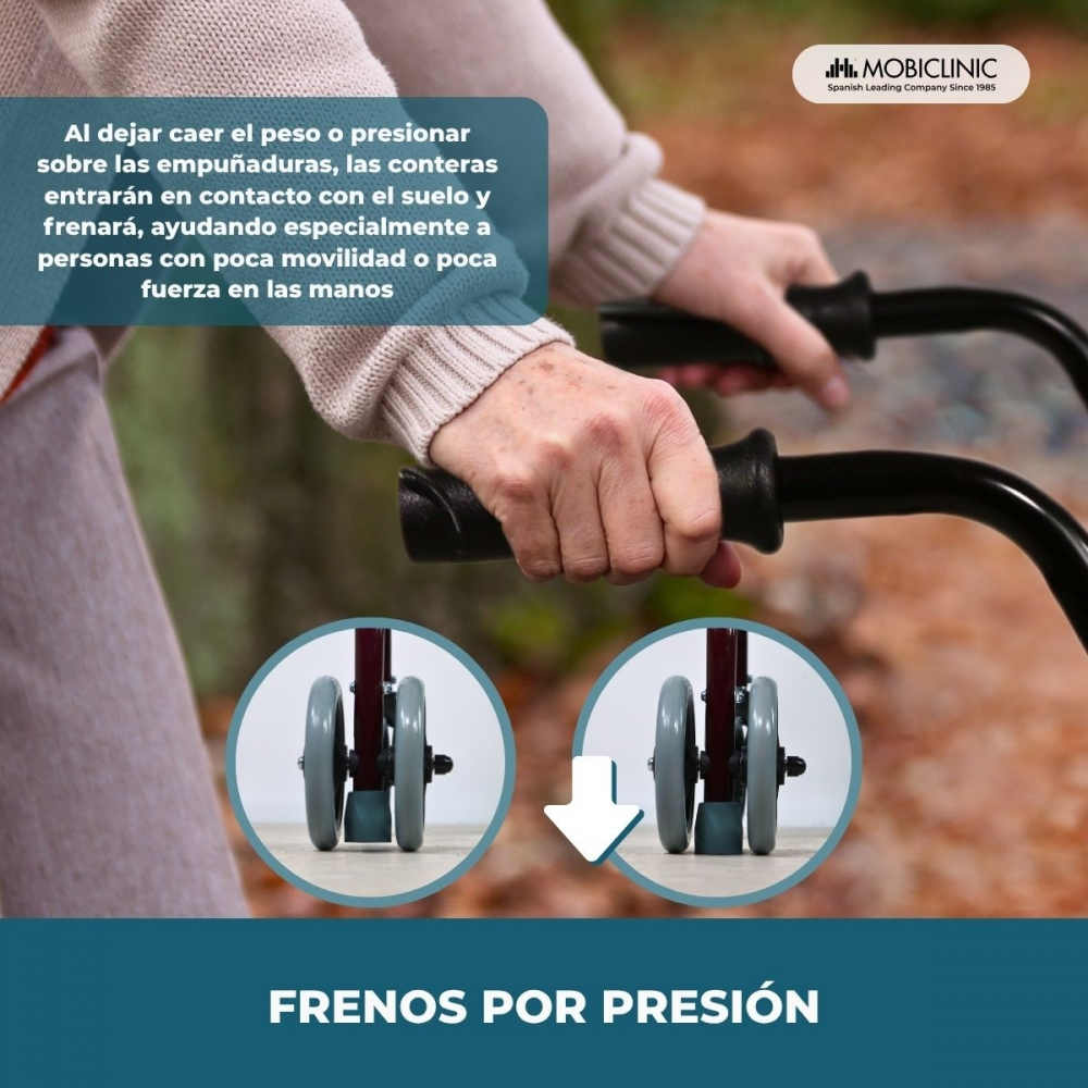 Primer plano de manos sujetando un andador con frenos de presión. Ruedas en detalle.