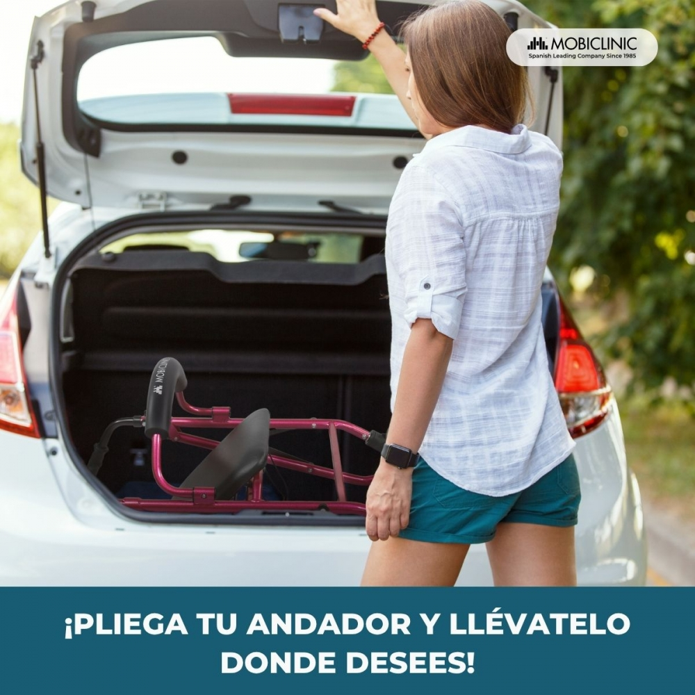 Una mujer carga un andador plegado en el maletero de un coche.