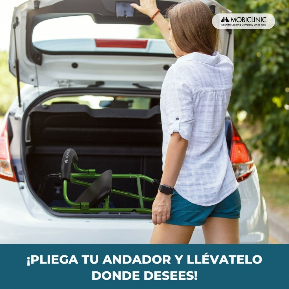 Mujer cargando andador verde en coche, maletero abierto.