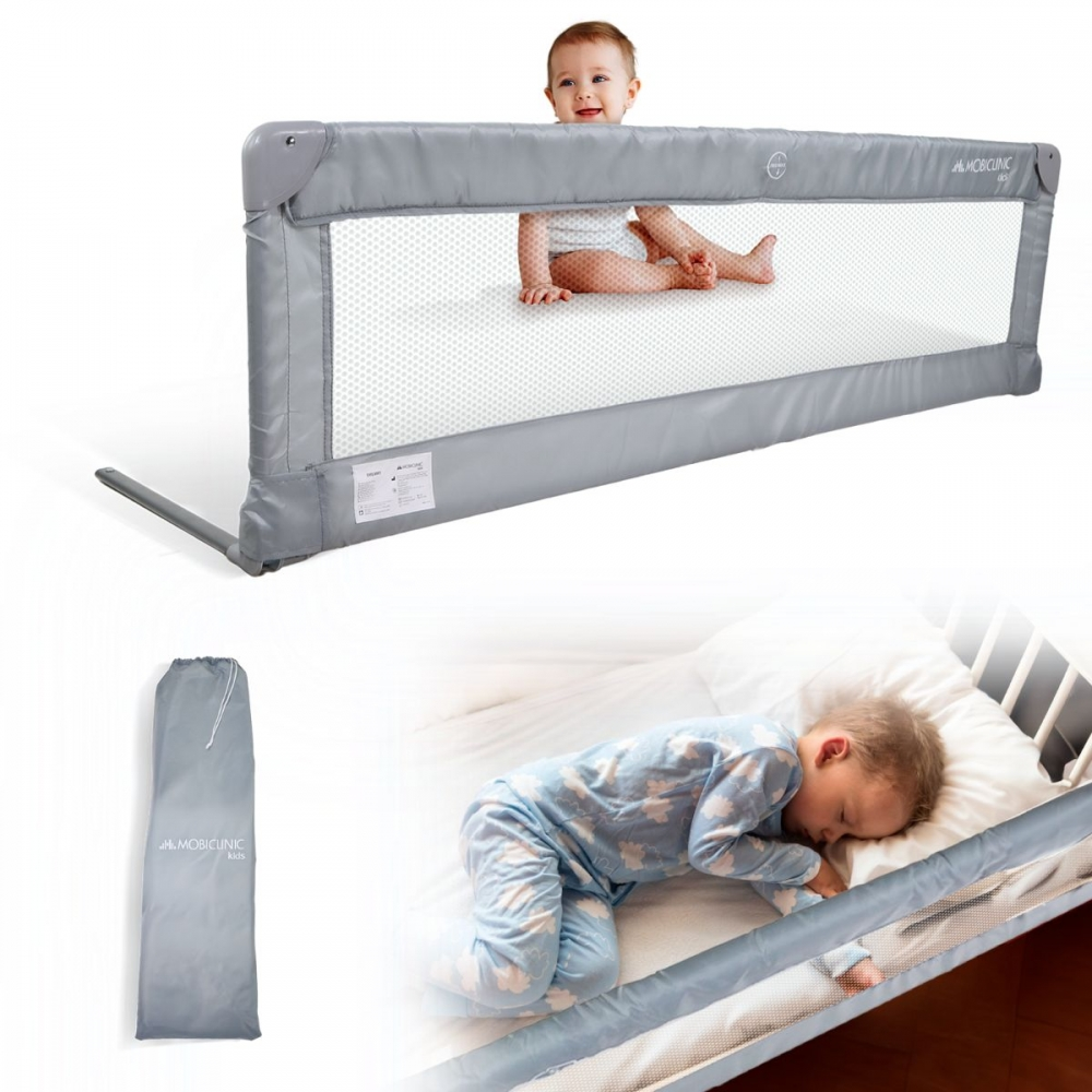Un bebé se sienta sobre una barrera de cama, un niño duerme en la cama.