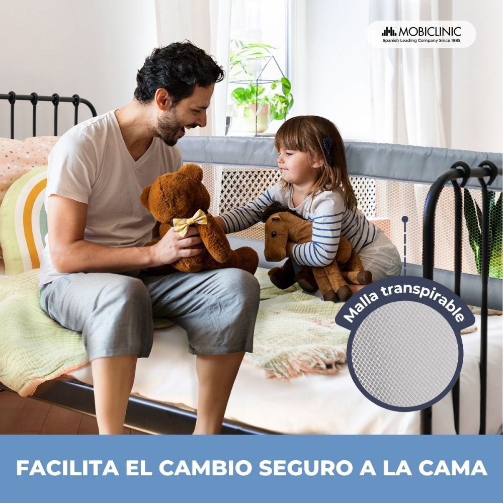Padre e hija sentados en la cama con peluches. Se ve una barrera de cama.