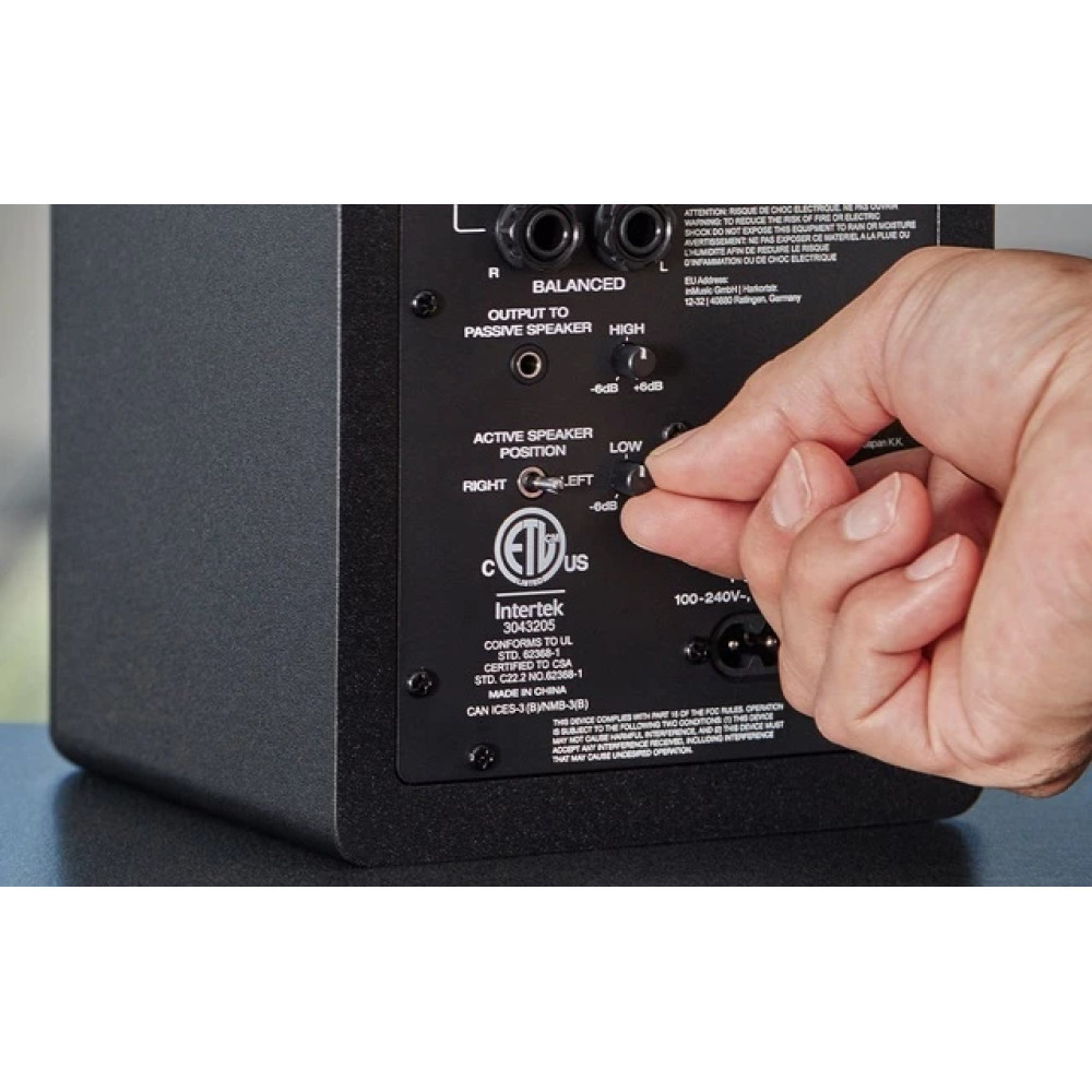 Dłoń reguluje pokrętło z tyłu głośnika, ustawiając pozycję aktywnego głośnika.