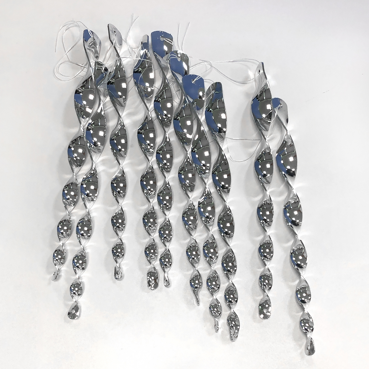 Shiny, spiral-shaped hanging decorations with strings on a white background.
