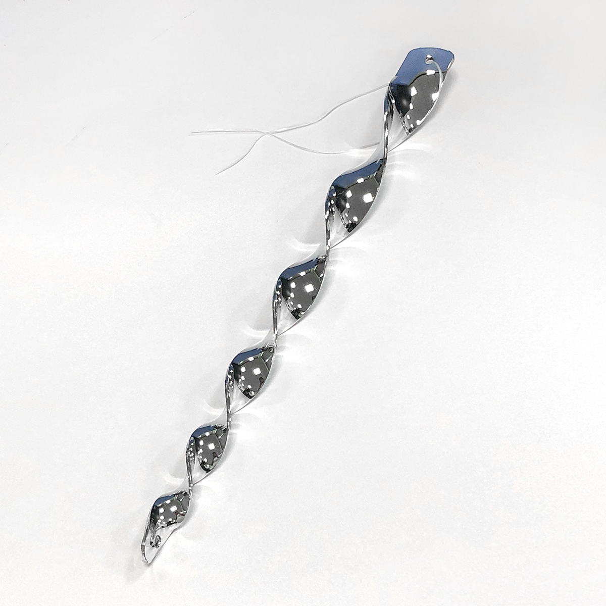 A shiny, spiral-shaped object with string on a white background.