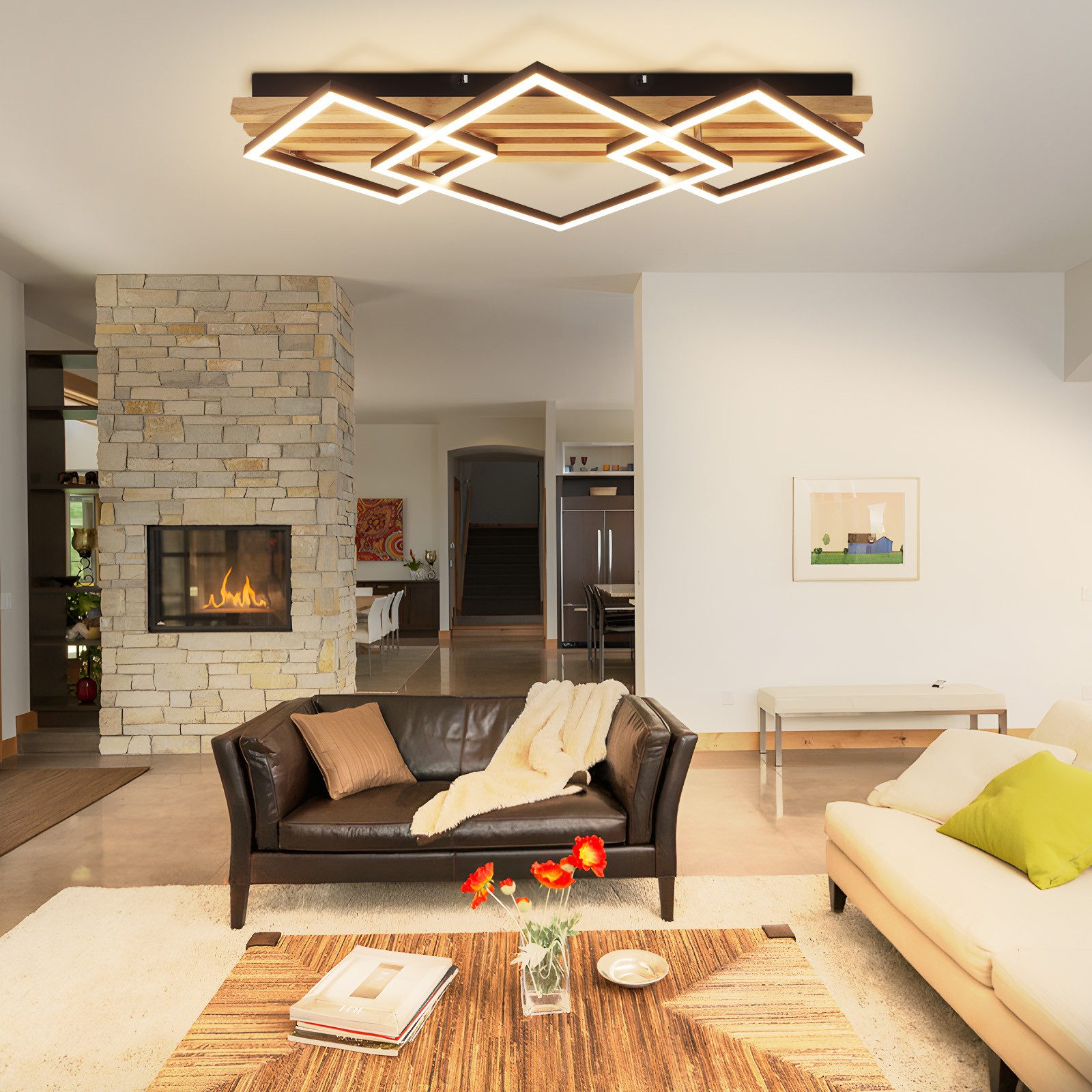 Ein Wohnzimmer mit Kamin, Ledersofa, Beigesofa und einem Holztisch.