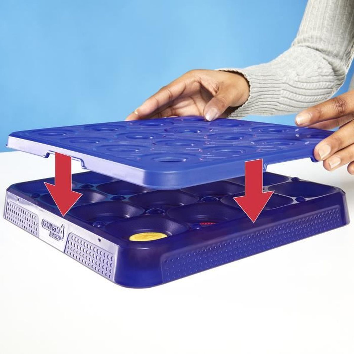 Blaue Spielschale mit Händen, die eine obere Abdeckung darauf legen.