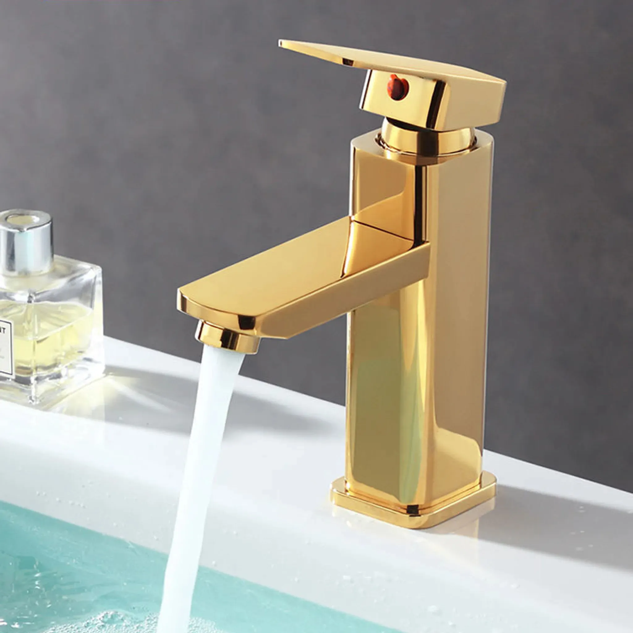 Goldener Wasserhahn mit laufendem Wasser auf einem weißen Waschbecken.