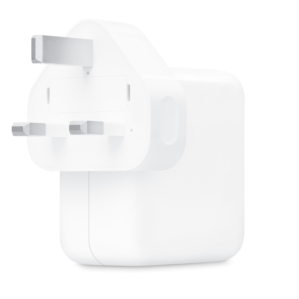 Un adaptateur secteur blanc avec trois broches argentées sur fond blanc.