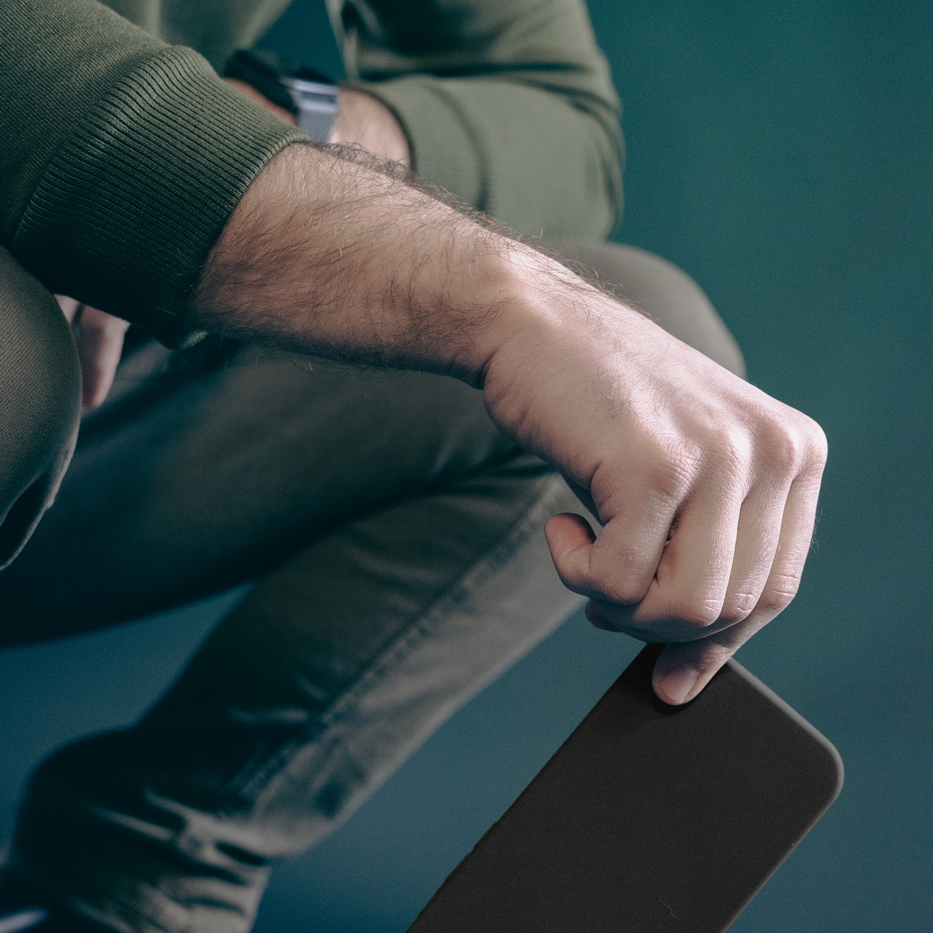 Osoba w khaki trzyma ciemny smartfon.