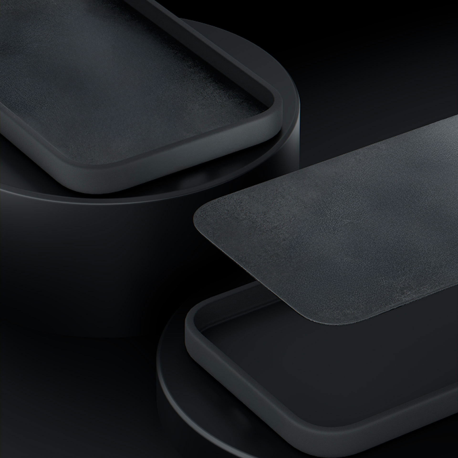 Trzy ciemne, prostokątne obiekty z zaokrąglonymi rogami na czarnym tle.