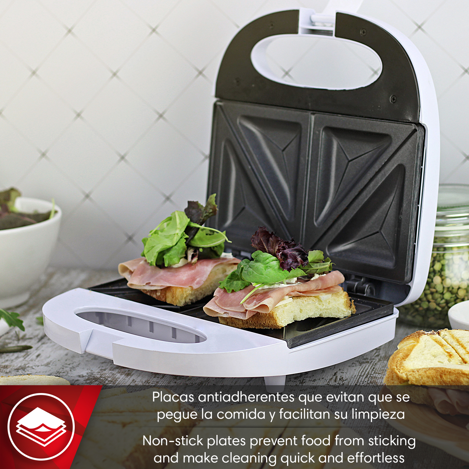 Una sandwichera abierta con dos sándwiches, cubiertos con jamón y verduras.