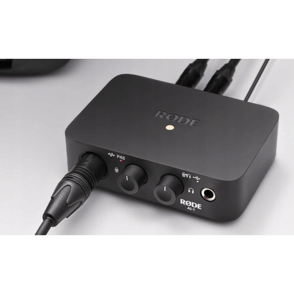 Czarny interfejs audio Rode AI-1 z pokrętłami, portami i kablami.