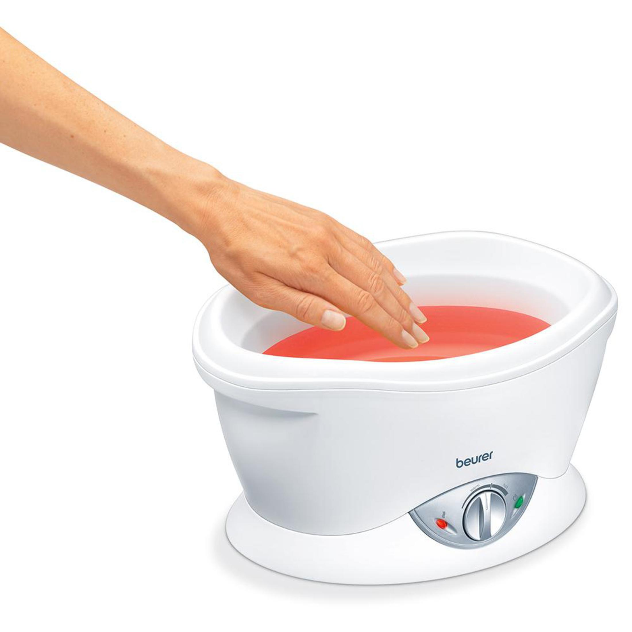 Eine Hand taucht in ein weißes Gerät mit roter Flüssigkeit.