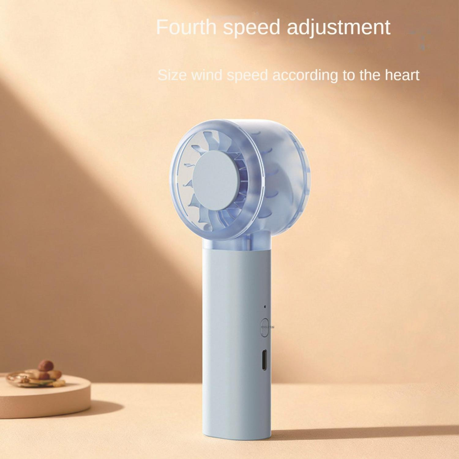 Ein blauer Handventilator mit transparentem Kopf steht auf einem hellbraunen Tisch.