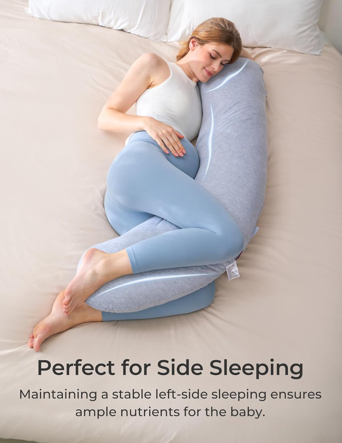 Femme enceinte dort sur le côté, entourée d'un coussin de corps.