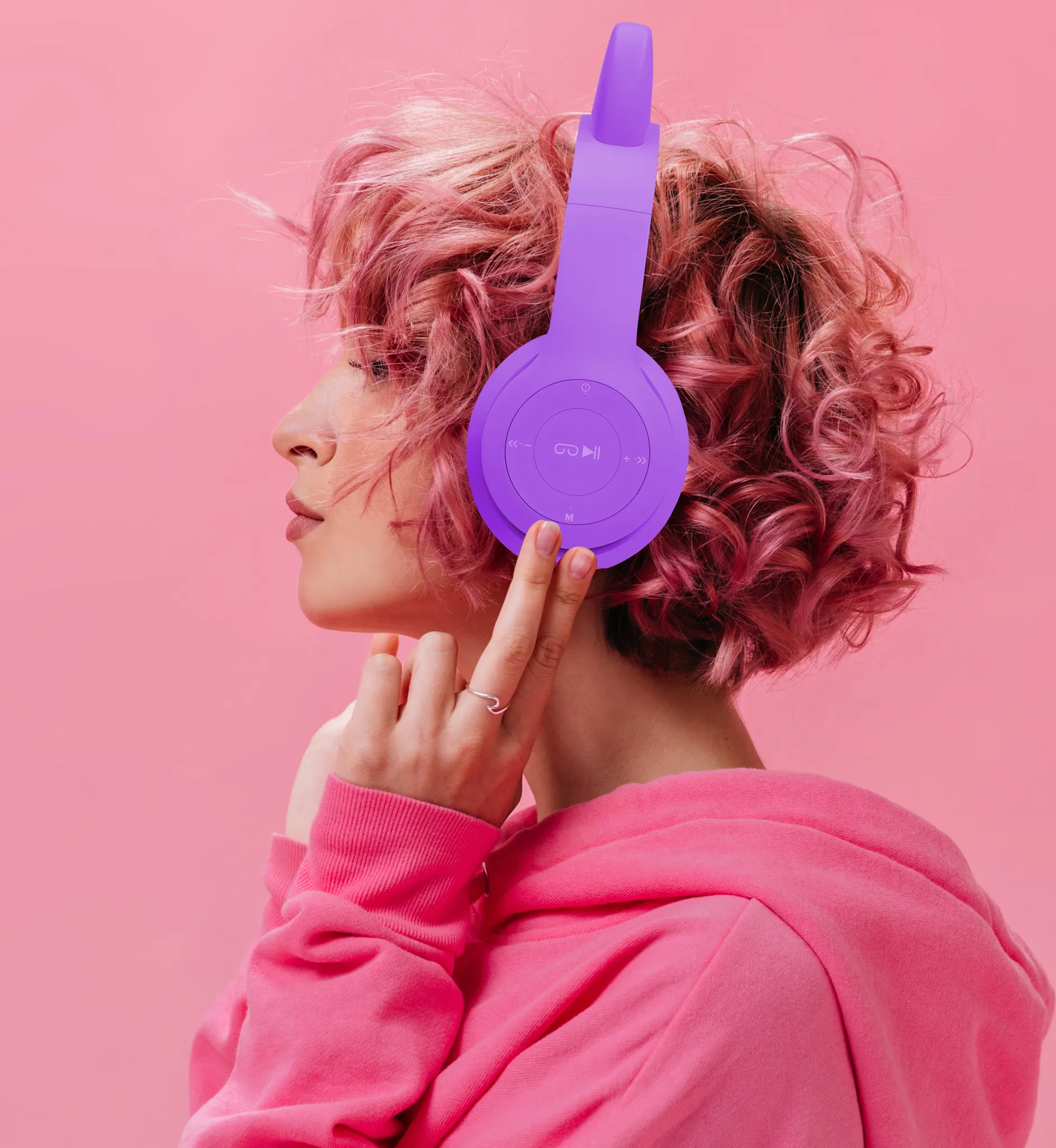 Frau mit pinken Haaren und Kopfhörern im Profil auf rosafarbenem Hintergrund.