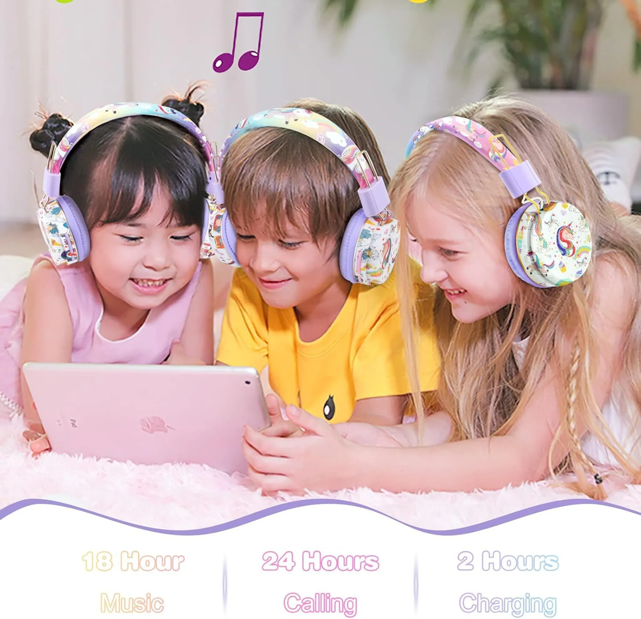 Drei Kinder tragen Einhorn-Kopfhörer und schauen auf ein Tablet auf einem flauschigen Teppich.