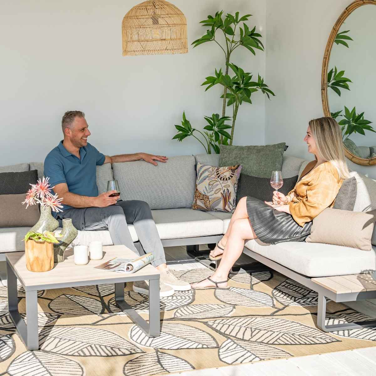 Un homme et une femme sont assis sur un canapé, tenant des verres et conversant.