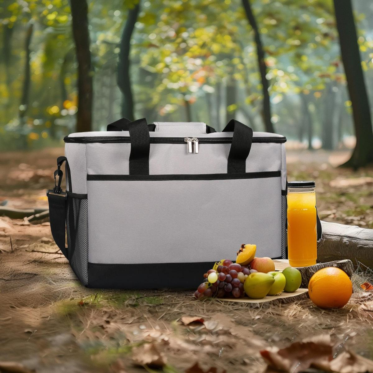 Graue Kühltasche mit Früchten und Saft im Wald.