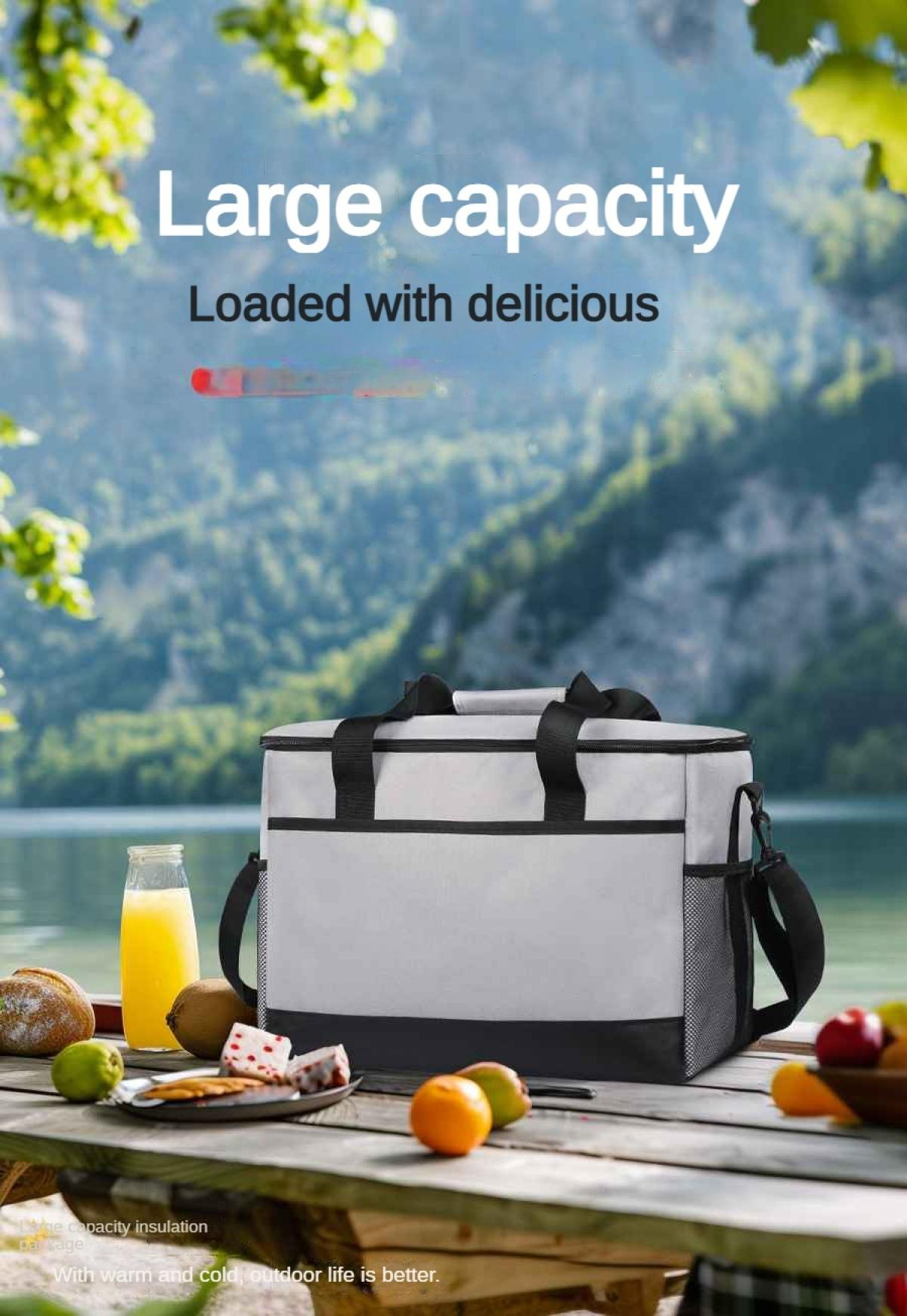 Graue Kühltasche mit Griffen auf einem Holztisch mit Obst und Brot.