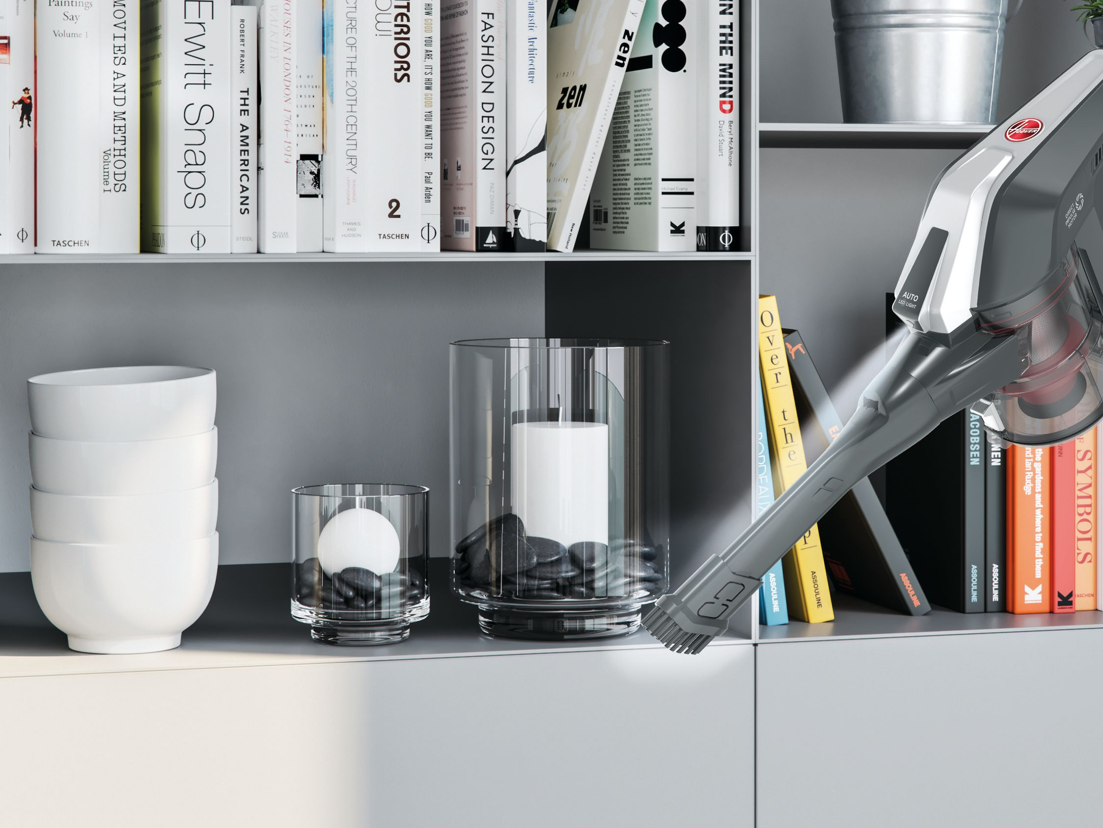 Ein Staubsauger reinigt ein Regal mit Büchern, Schalen und Kerzenhaltern.
