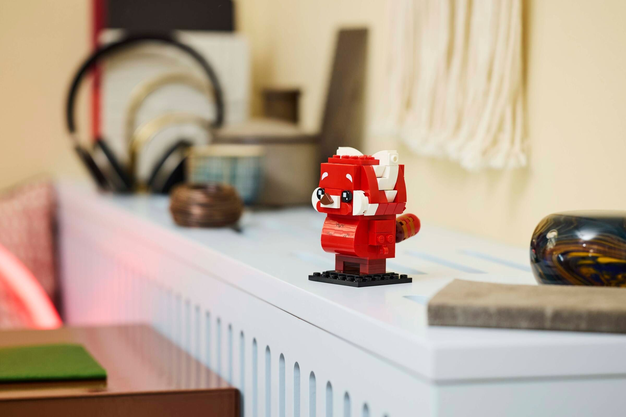 Ein roter Lego-Panda mit weißer Dekoration steht auf einem weißen Sims.