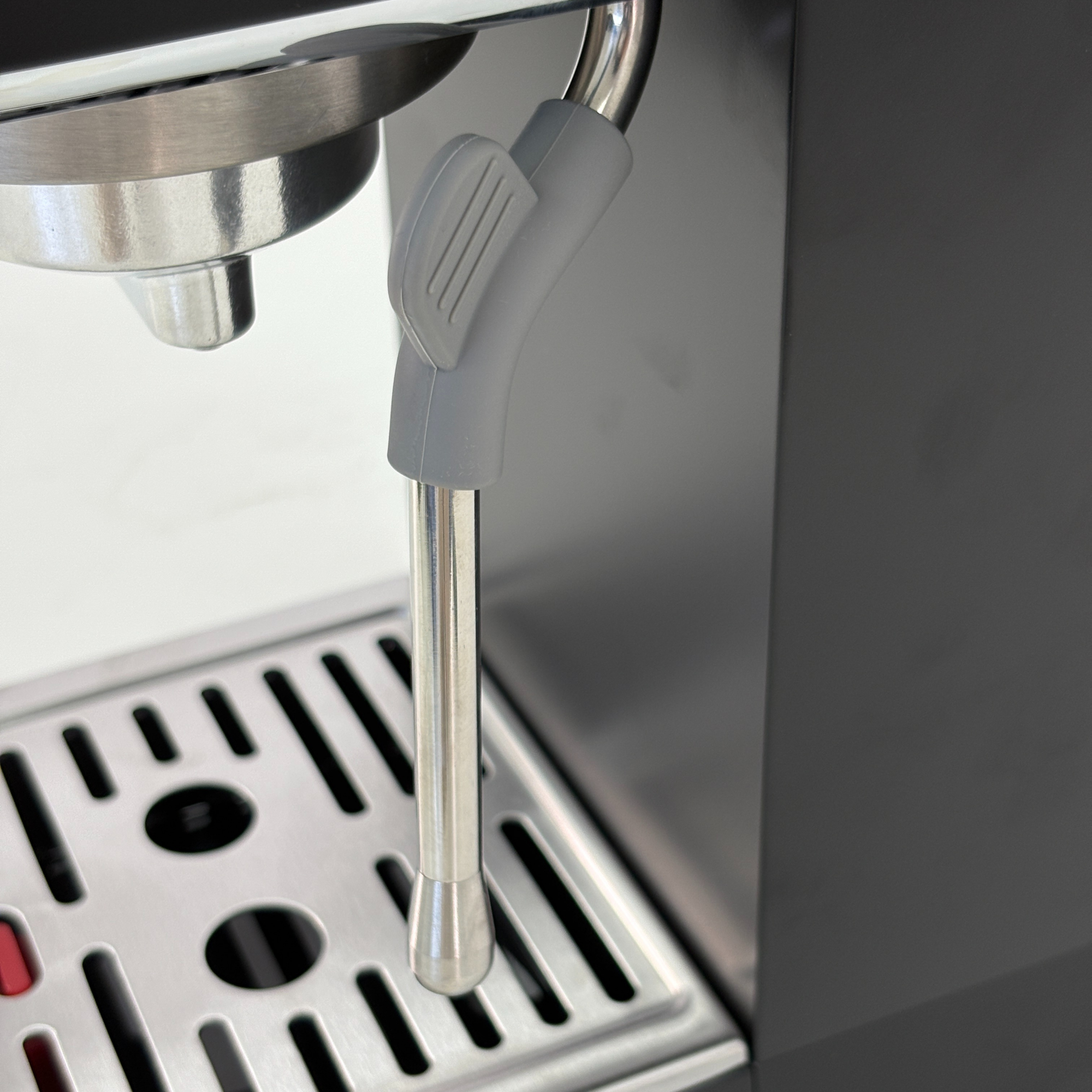 Primer plano de lanza de vapor de máquina de espresso sobre bandeja de goteo.