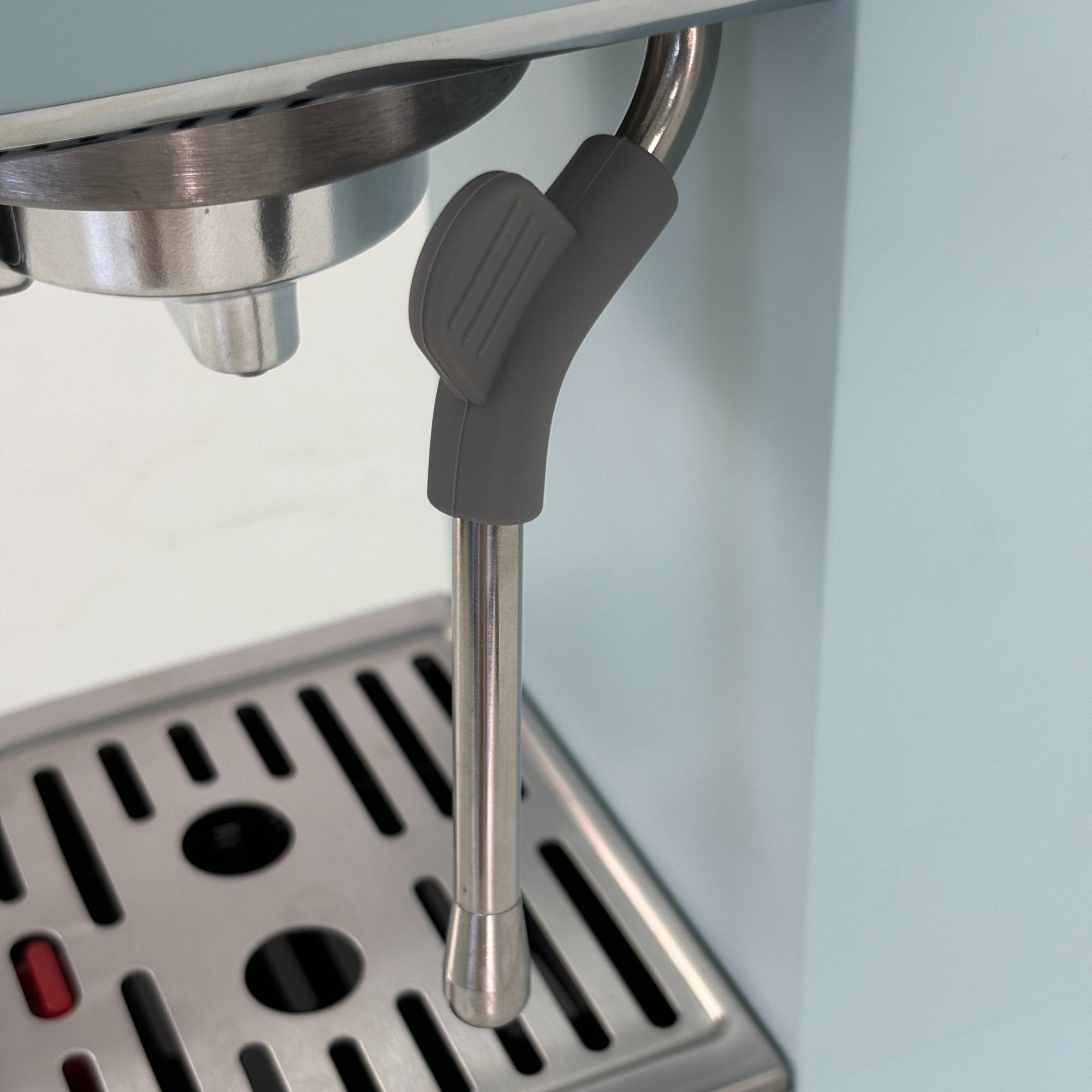 Primer plano de una cafetera expreso, se ve la lanza de vapor y la bandeja.
