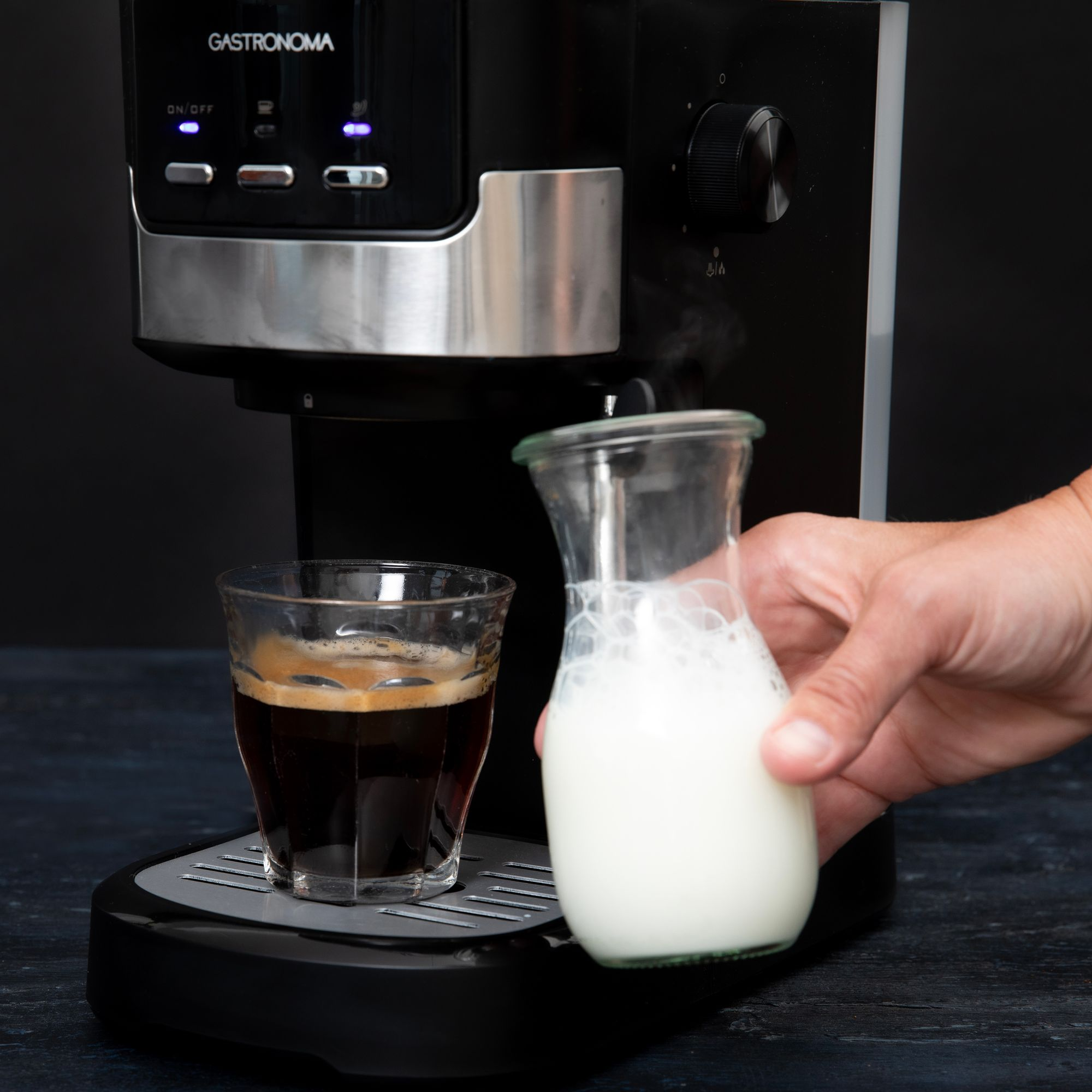 Para unosi się z ekspresu do kawy przelewającego mleko do szklanki.