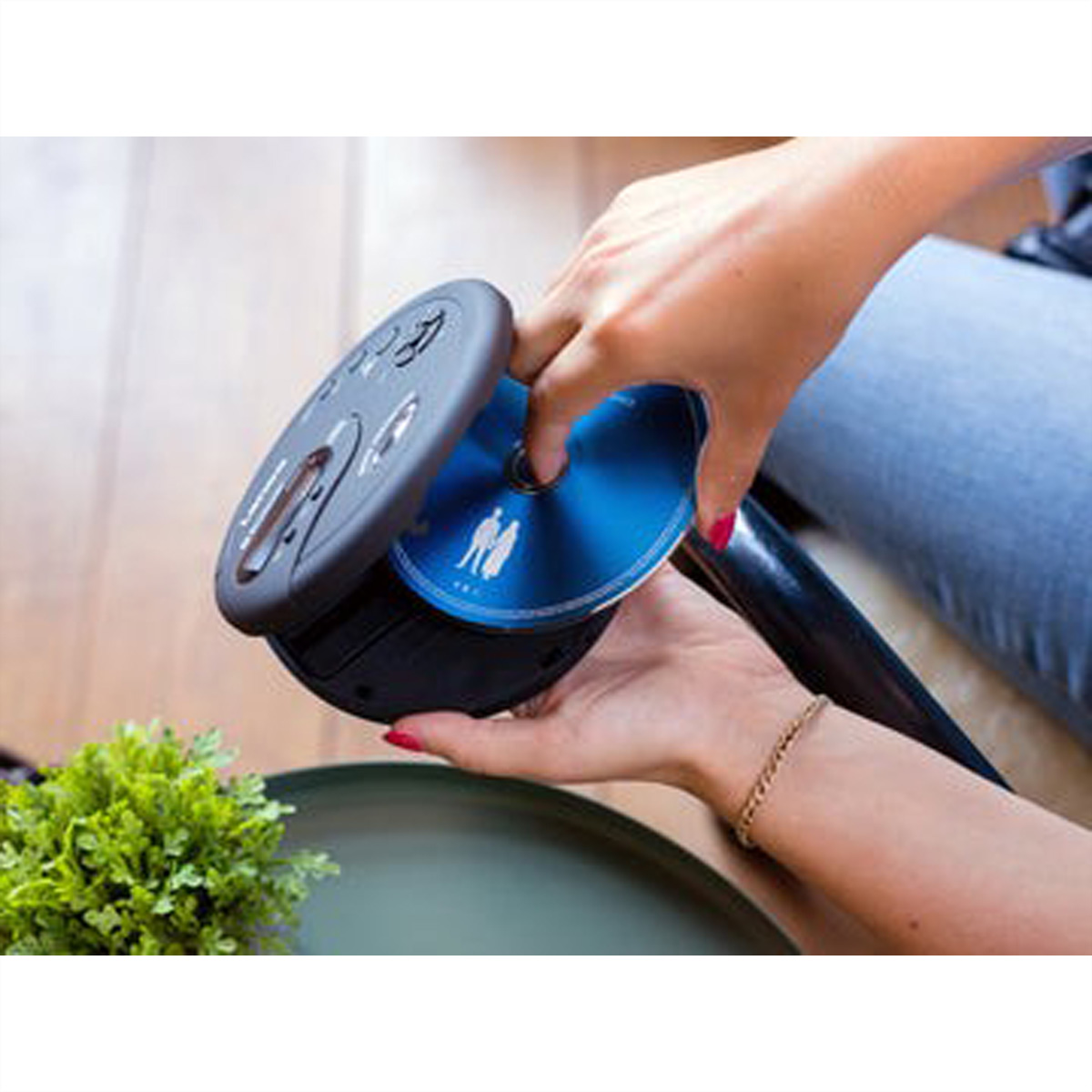 Osoba wkłada niebieski dysk CD z białym symbolem do przenośnego odtwarzacza CD.