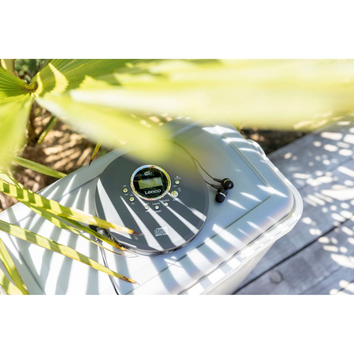 Odtwarzacz CD Lenco ze słuchawkami spoczywa na szarym pudełku.