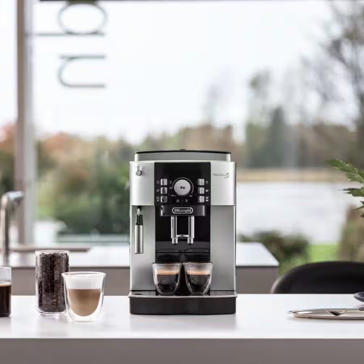 Srebrna ekspres do kawy parzy dwa espresso w szklankach na stole.