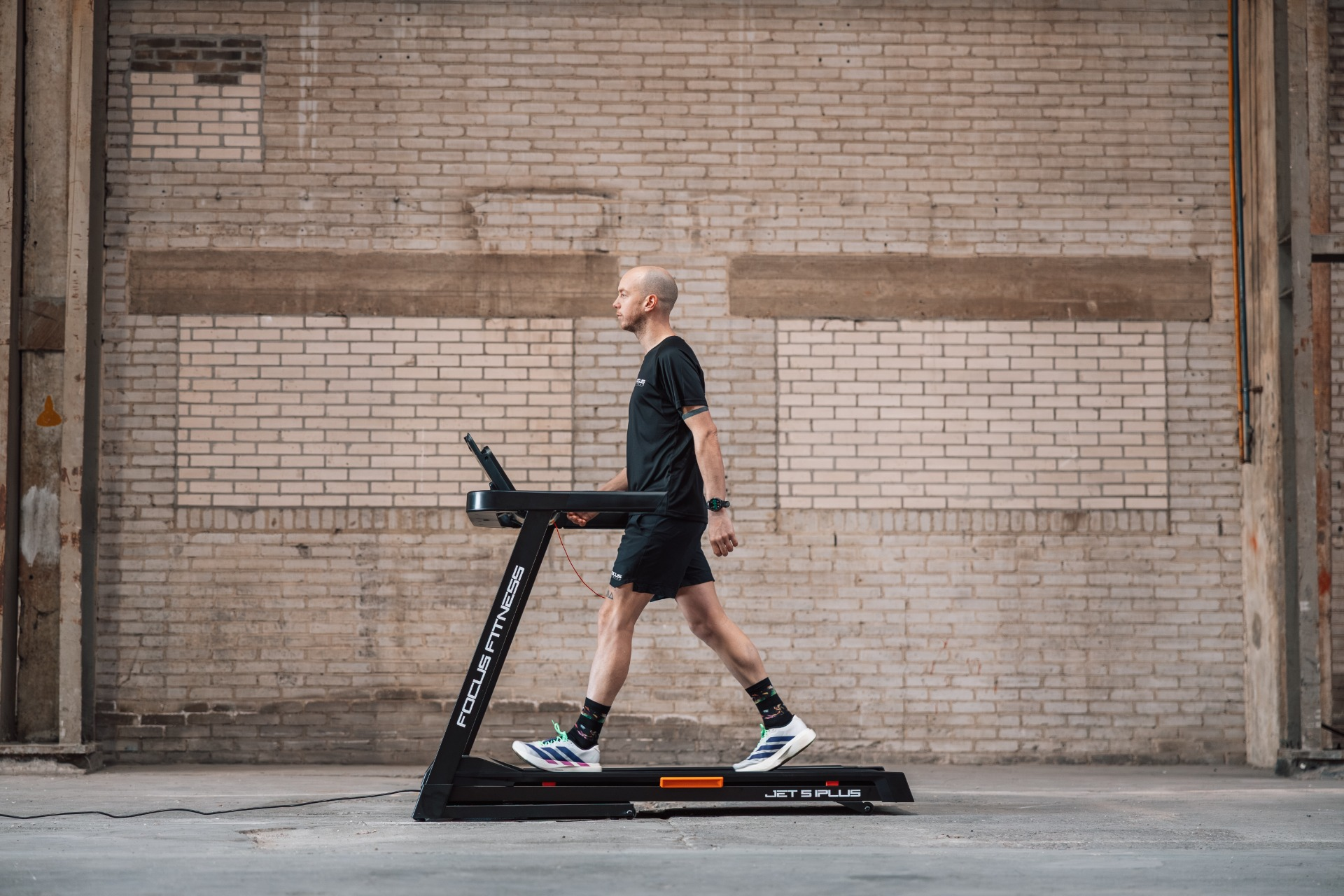 A man on a treadmill in a brick building.