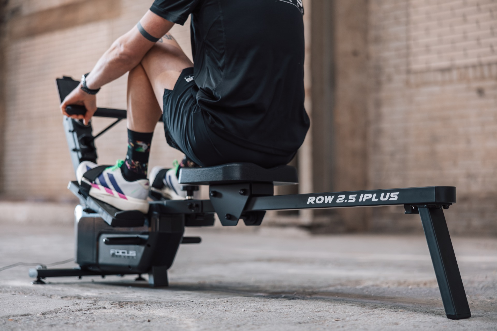 Persoon op roeimachine. Focus op benen, voeten en machine details.