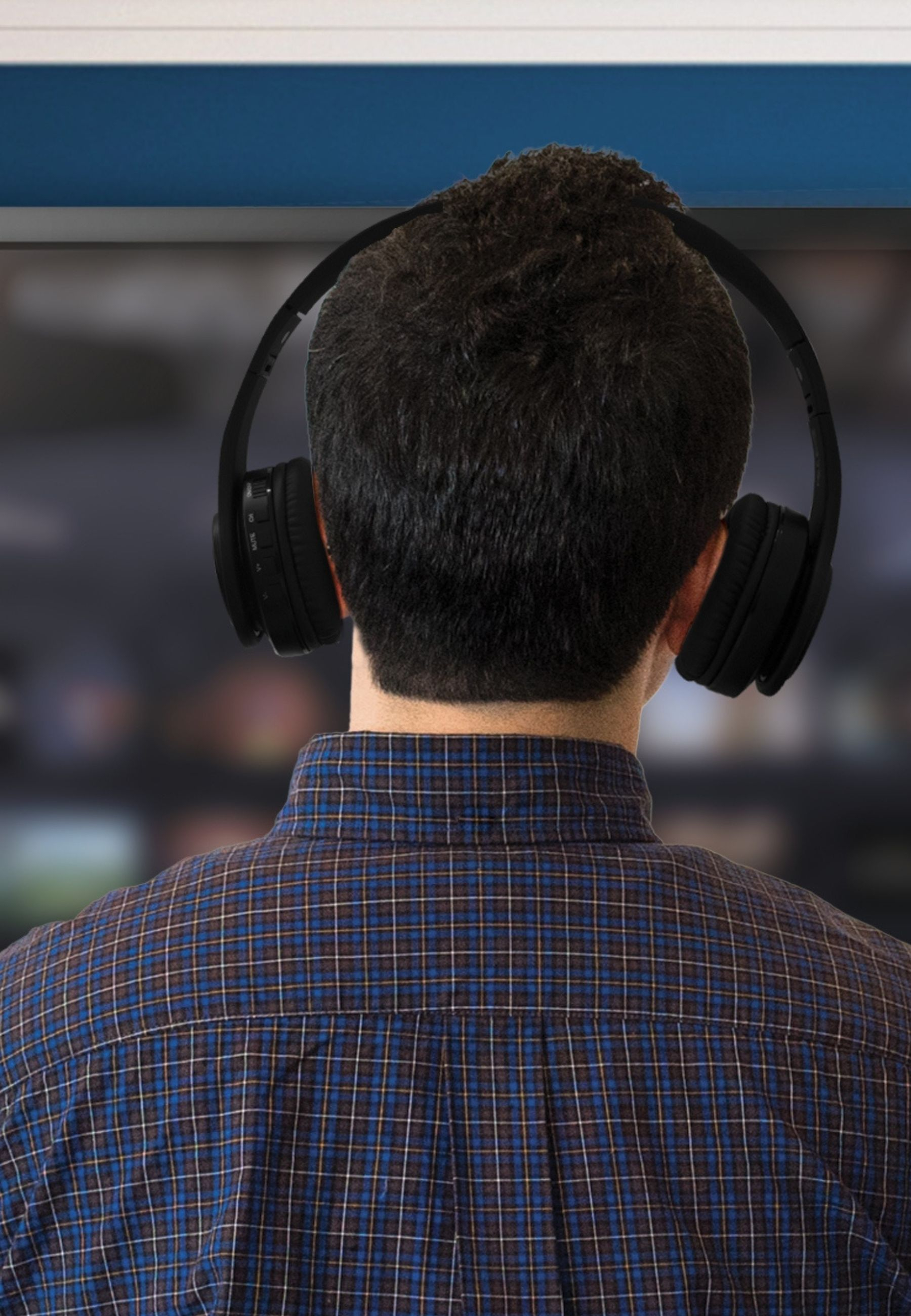 Mężczyzna w słuchawkach, widziany od tyłu, nosi koszulę w kratę.