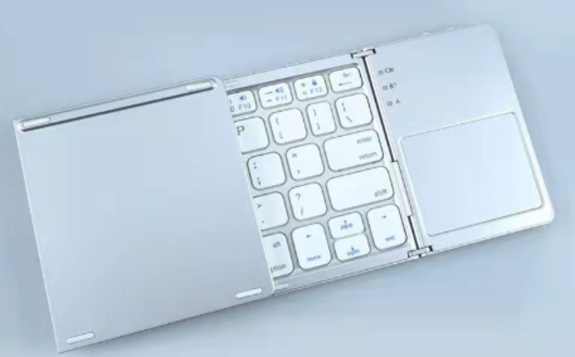 Ein silbernes faltbares Keyboard mit Touchpad auf grauem Hintergrund.