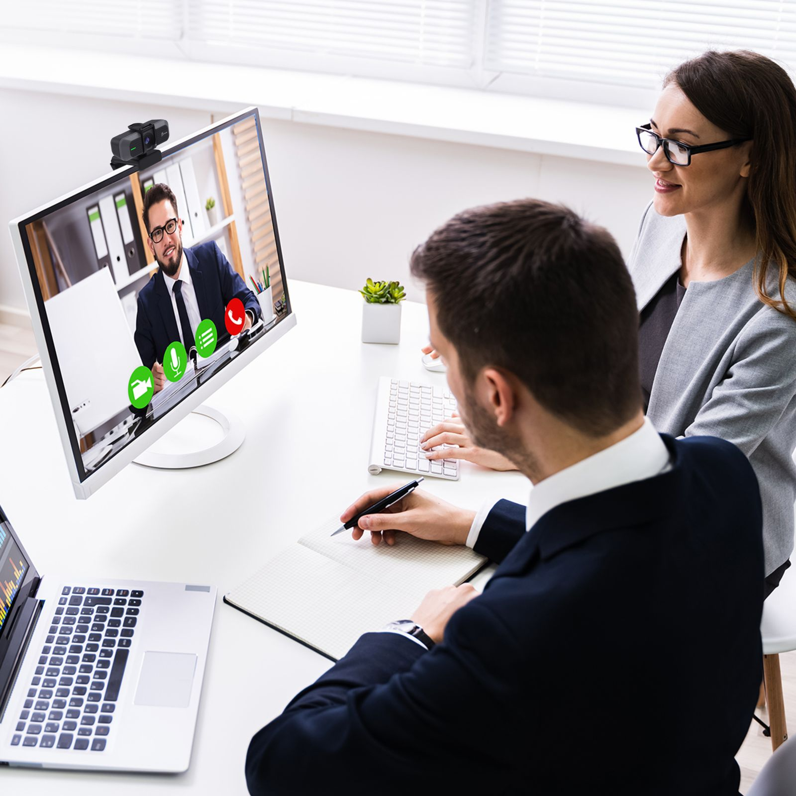 Zwei Personen führen eine Videokonferenz. Ein Mann lächelt. Ein Laptop ist offen.