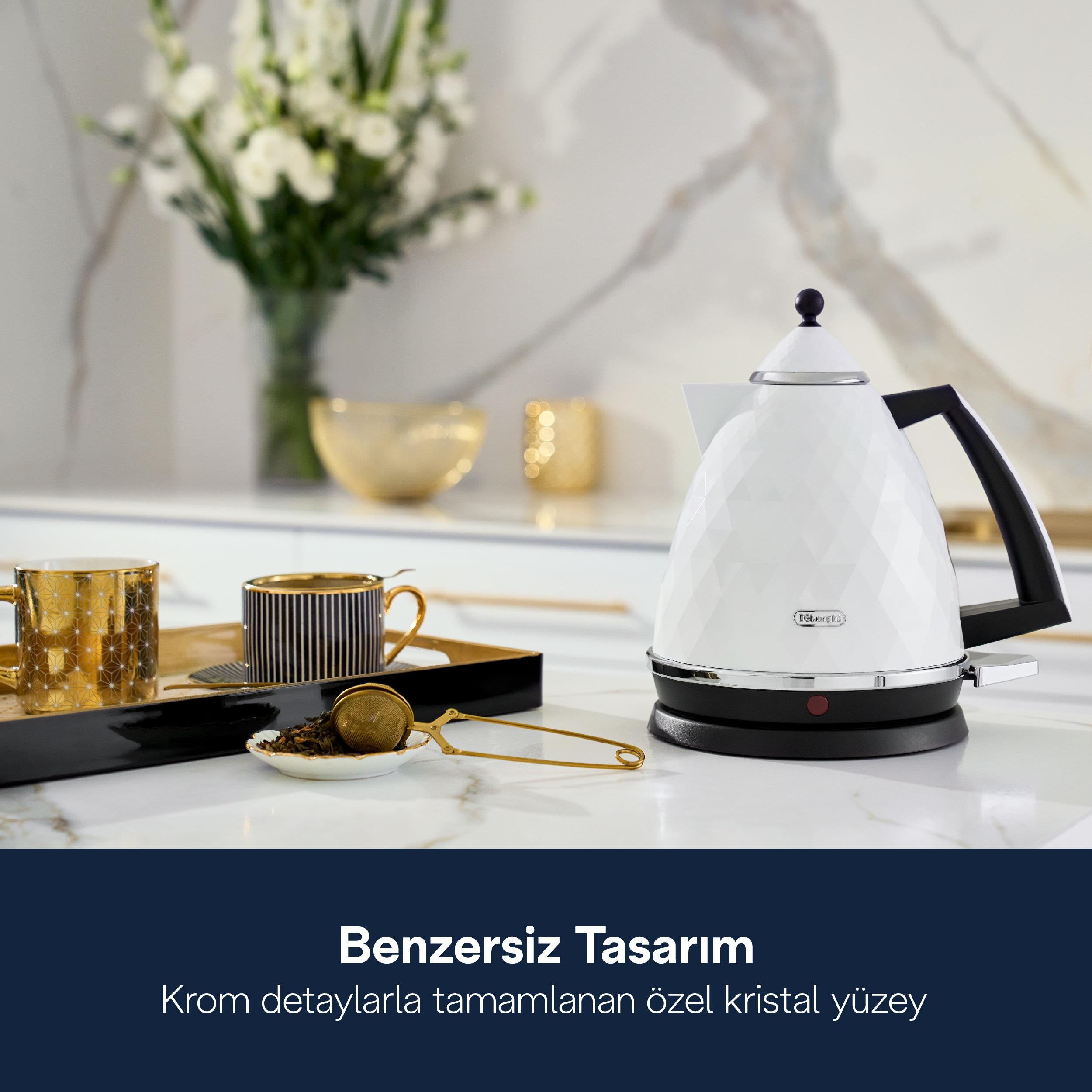 Fasetli beyaz su ısıtıcı, altın rengi fincanlar ve mermer tezgah.