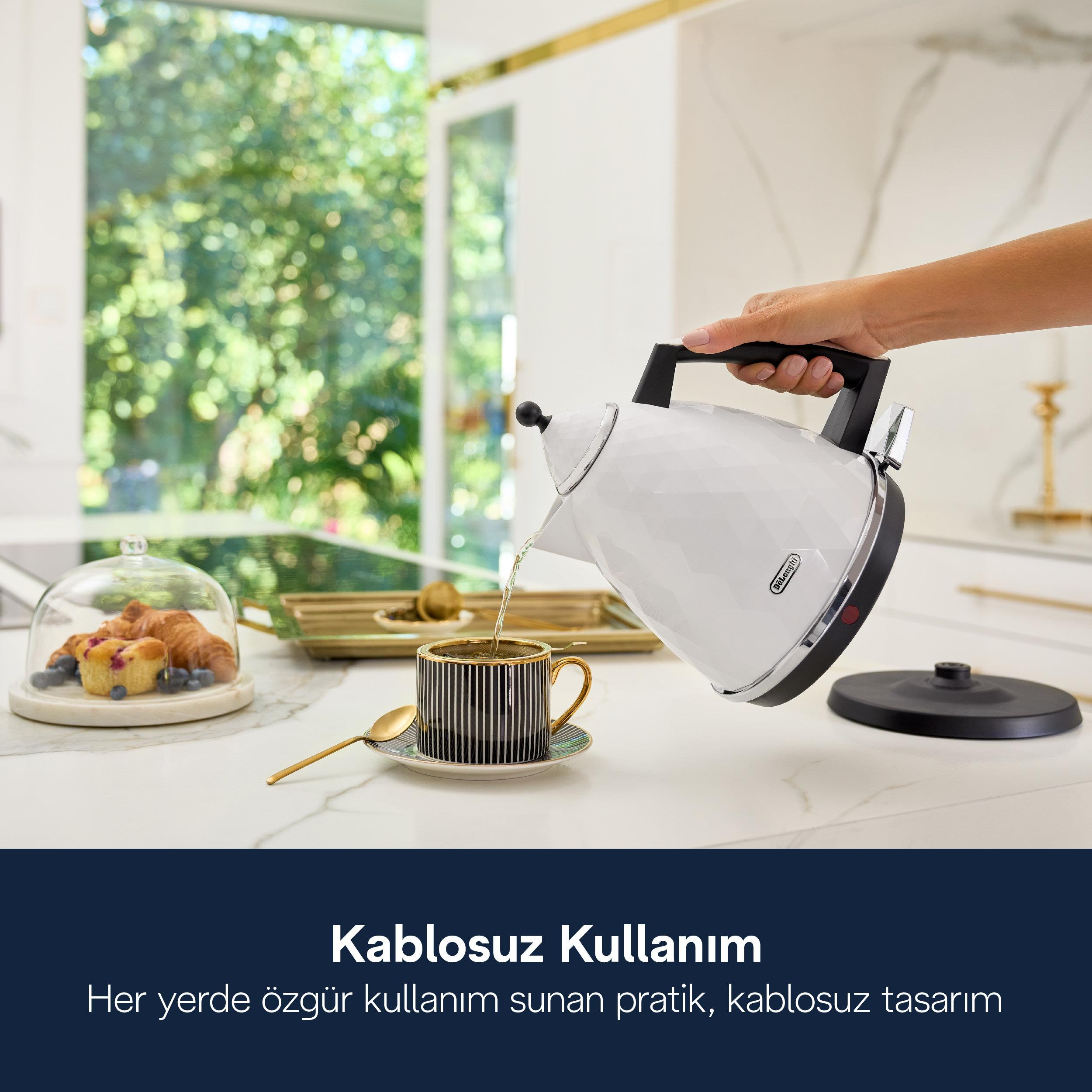 Bir el, beyaz bir su ısıtıcısından çizgili bir fincana su döküyor.