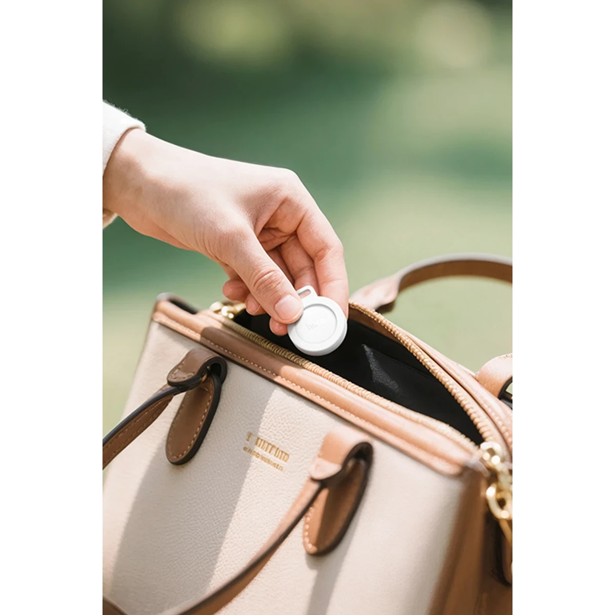 Hand legt weißen Tracker in beige Tasche. Bokeh Hintergrund.