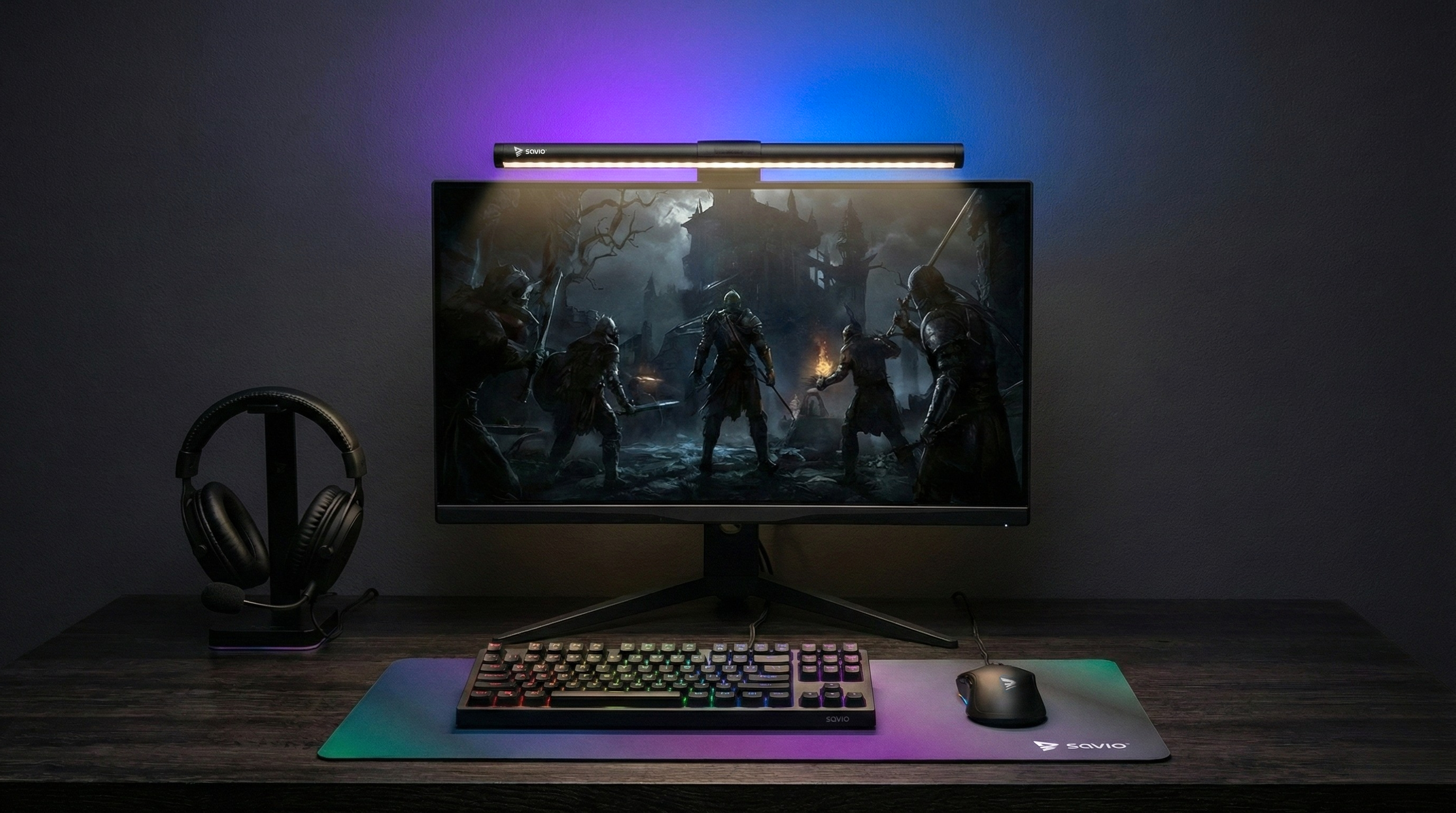 Biurko z monitorem wyświetlającym grę, klawiaturą, myszą i słuchawkami, oświetlone lampą.