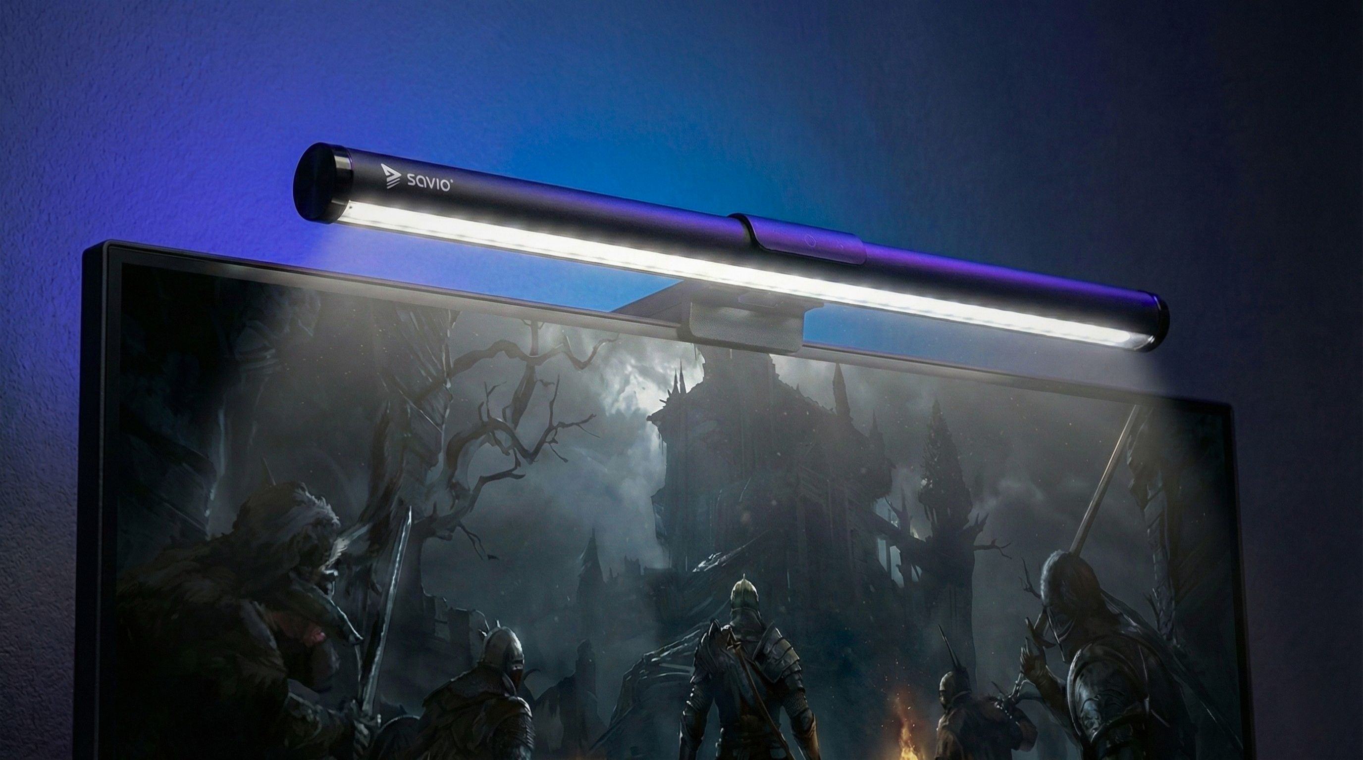 Lampa monitora świeci nad ciemnym ekranem fantasy z rycerzami.