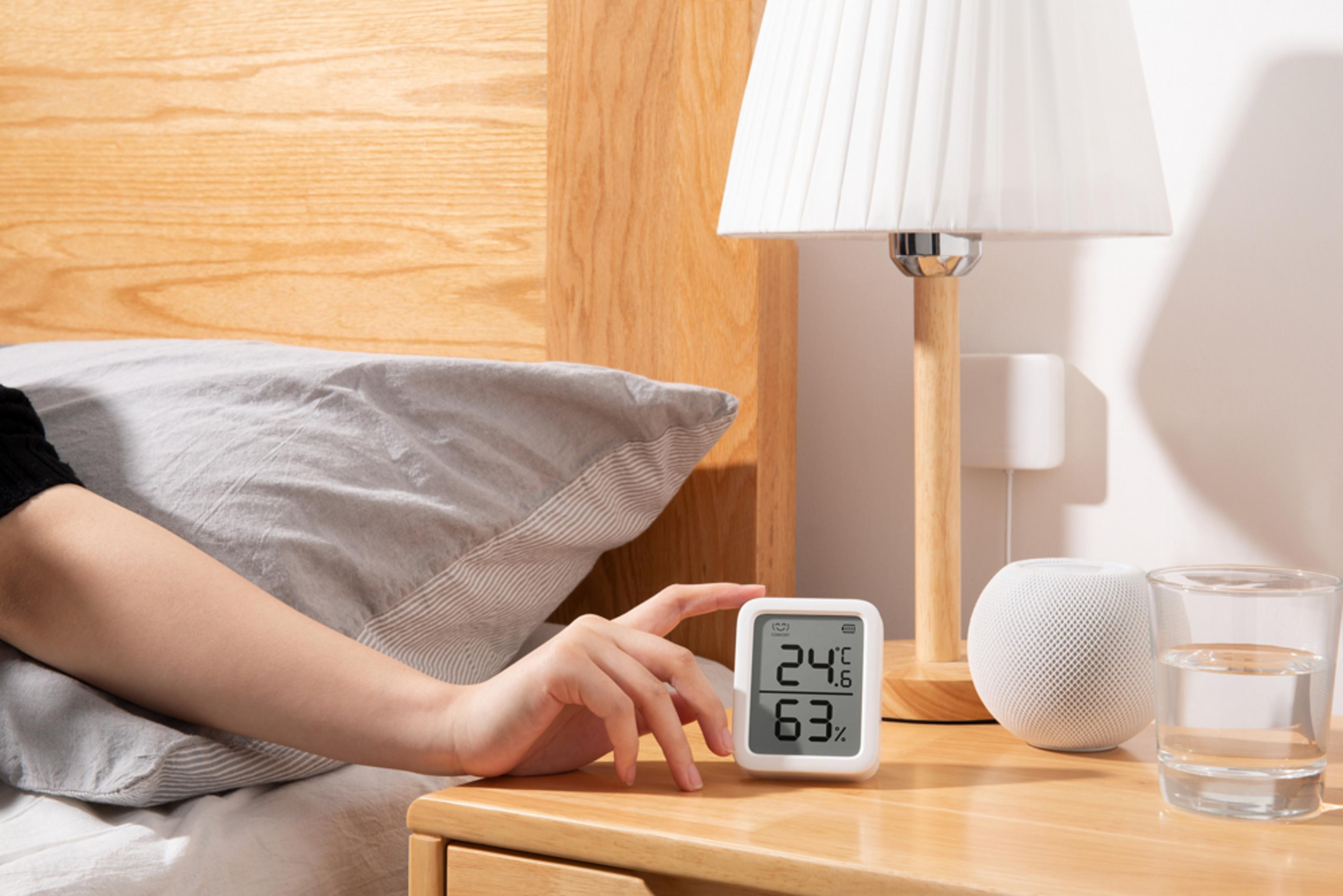 Ein Thermometer zeigt 24.6°C und 63% Luftfeuchtigkeit an. Daneben stehen ein Lautsprecher und ein Glas Wasser.