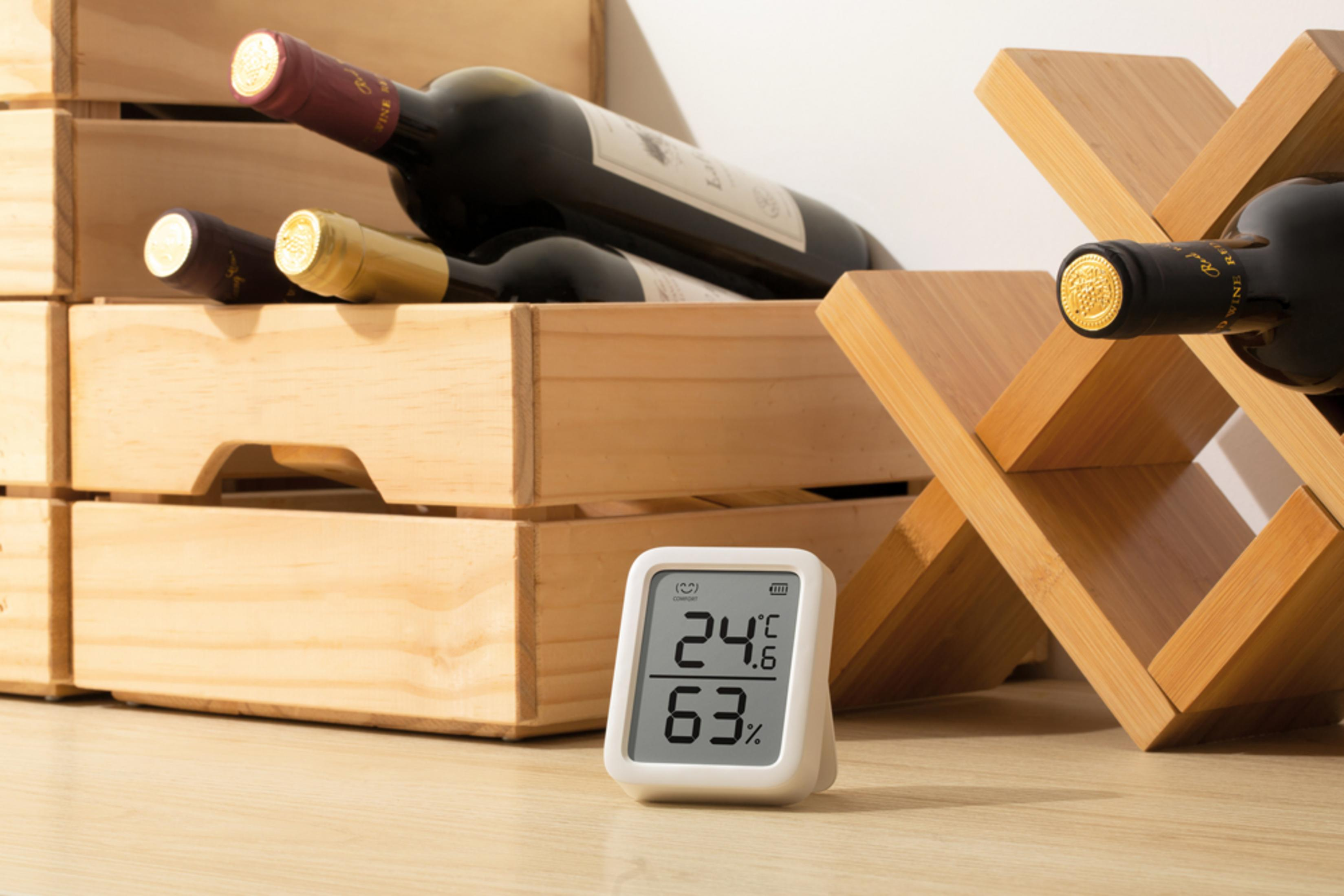 Wein und ein Hygrometer in Holzkisten und einem Holzständer.