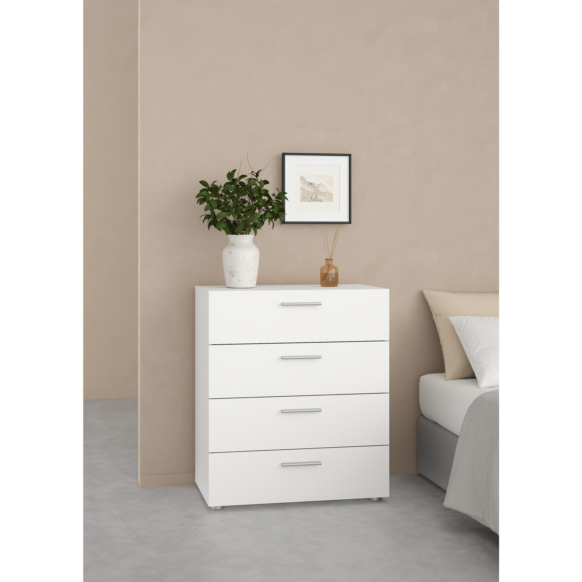 Cómoda blanca de cuatro cajones junto a una cama con almohadas.